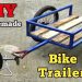 Homemade bicycle cargo trailer made from blue metal frame and wooden planks attached to a bike.