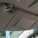 A close-up view of a car’s sun visor mounted above the windshield, showing the hinge and clip mechanism used for removal and replacement.