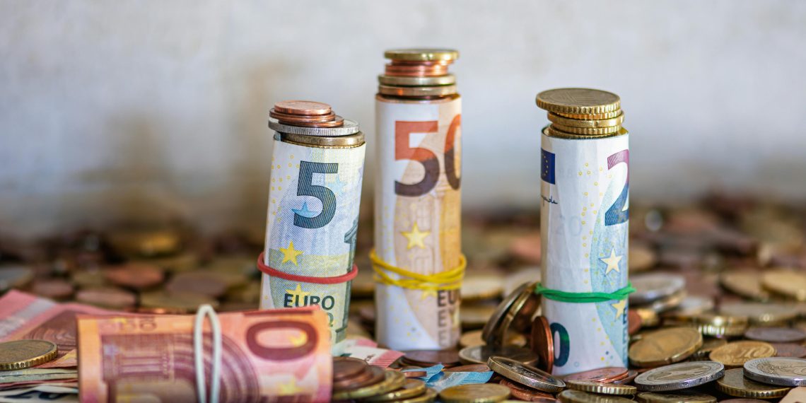 Rolled euro banknotes and stacked coins on a table representing savings, investments, and financial growth.